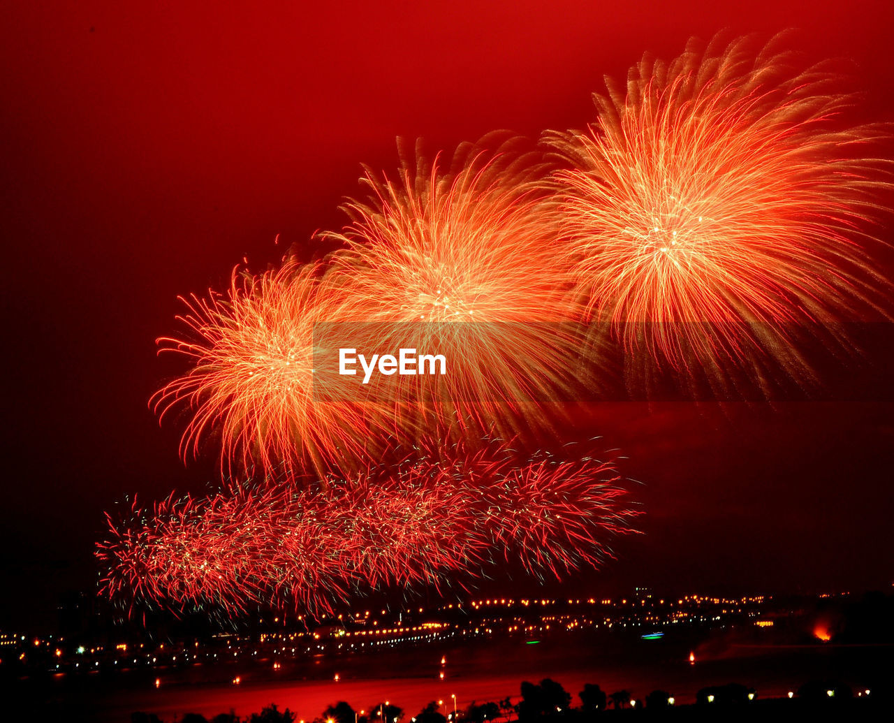 Firework display over river in illuminated city at night