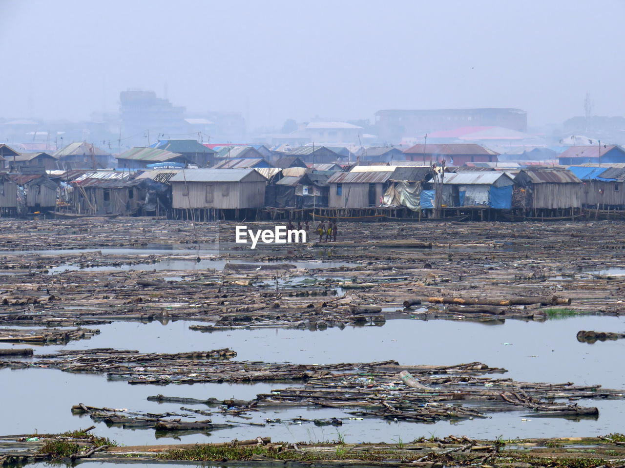 Huts at dirty beach against sky