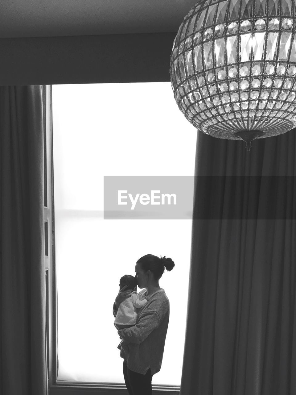 Mother kissing daughter while standing at home