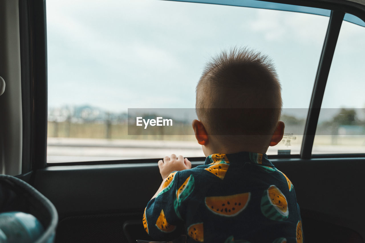 Young boy waiting for airplane landing inside the car