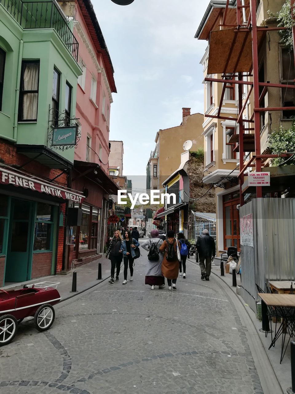 PEOPLE WALKING ON STREET AMIDST BUILDINGS