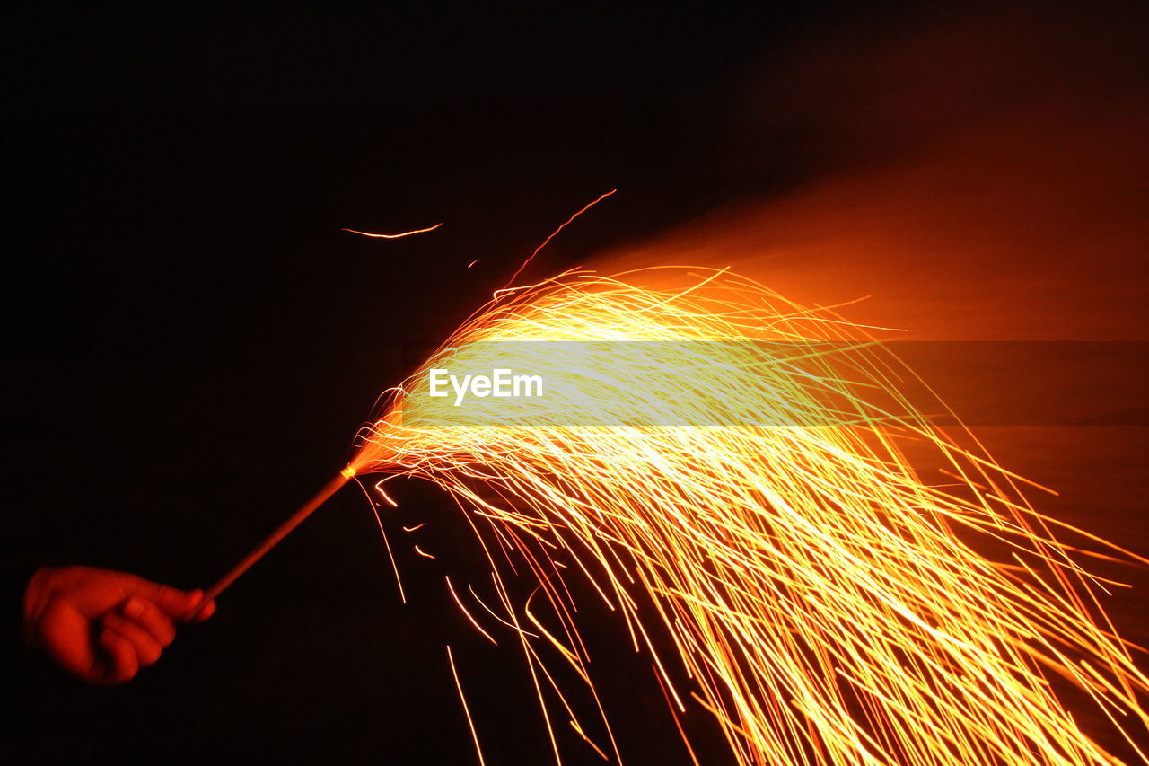 Cropped hand of person holding firework at night