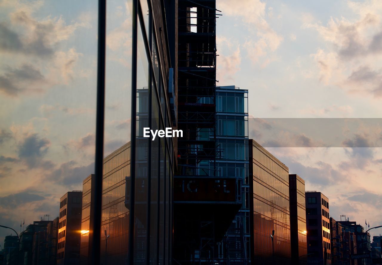 LOW ANGLE VIEW OF MODERN BUILDINGS AGAINST SKY AT SUNSET