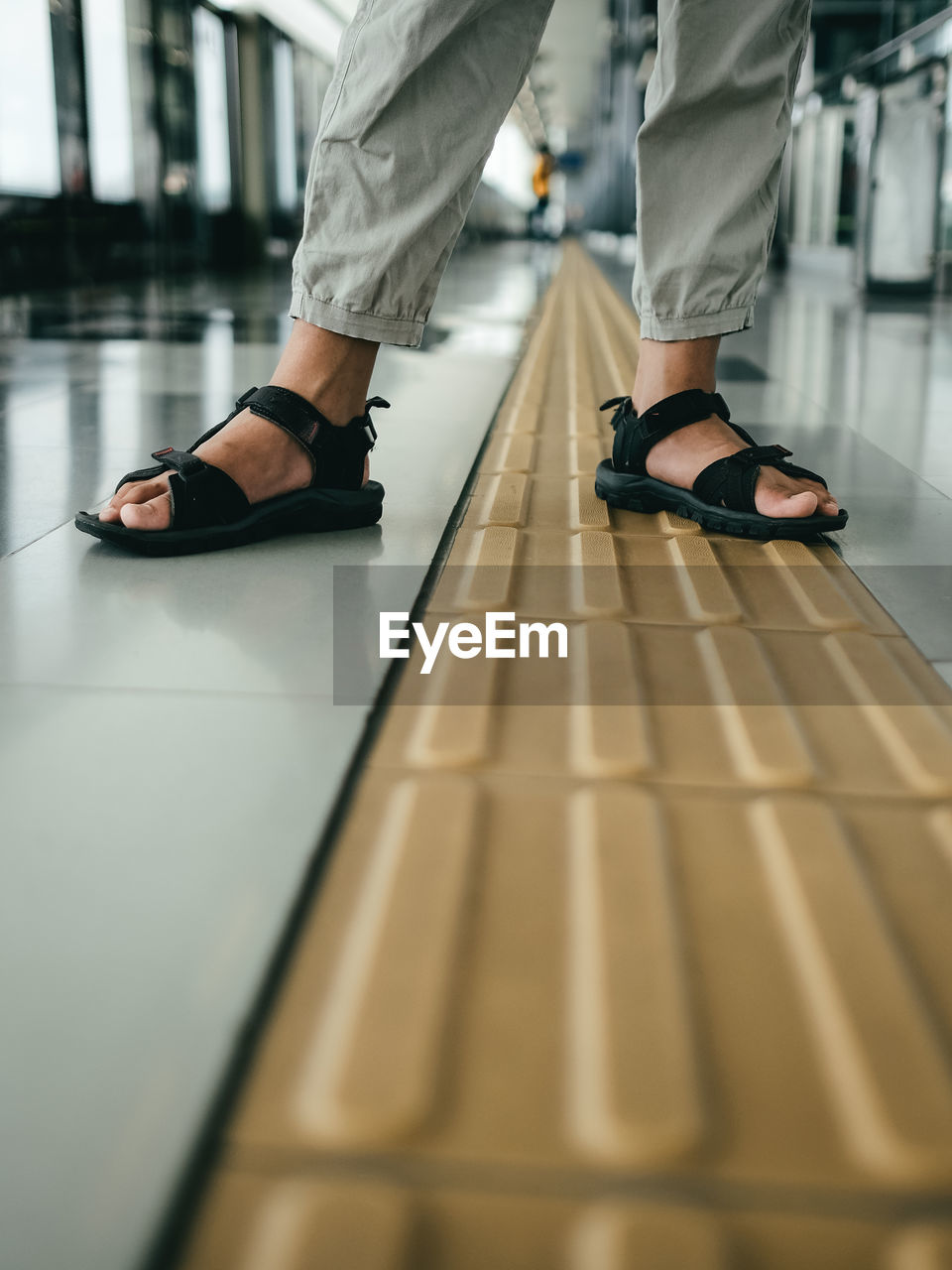 Low section of a boy standing waiting for a train 