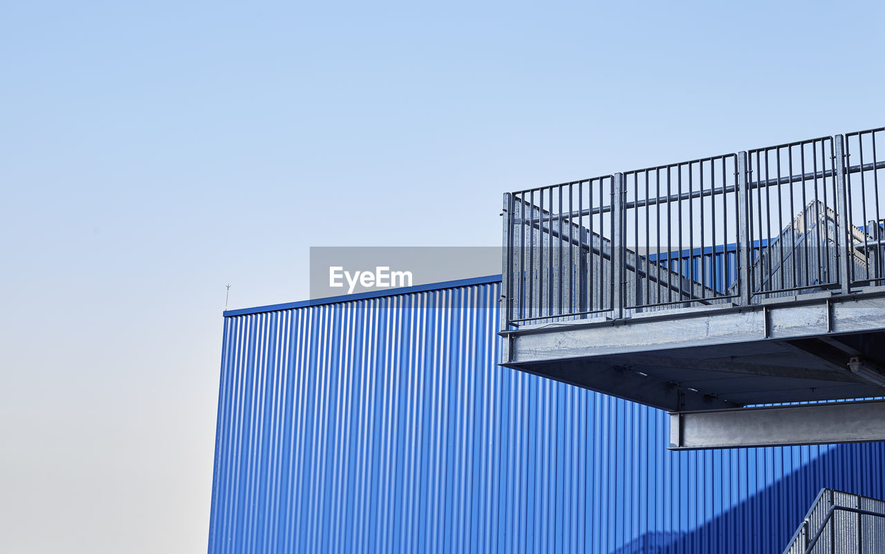 Low angle view of factory against clear blue sky