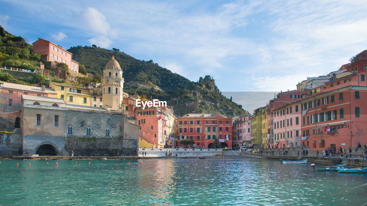 Buildings by river against sky in city