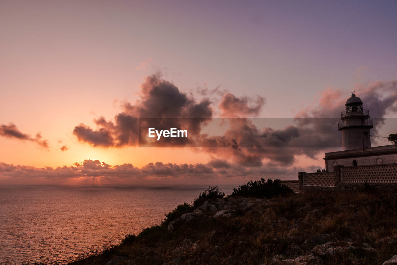 Scenic view of mediterranean sea and lighthouse against sky during sunrise at san antonio cape 