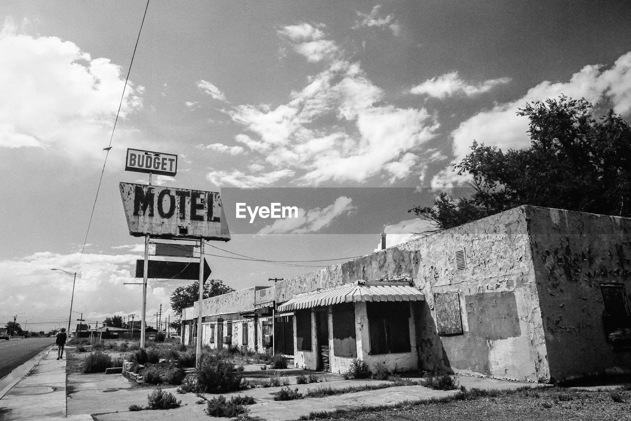 Low angle view of road sign on abandoned building against sky