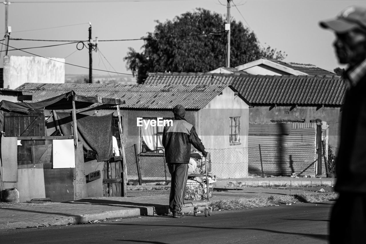 Men on road against houses and sky