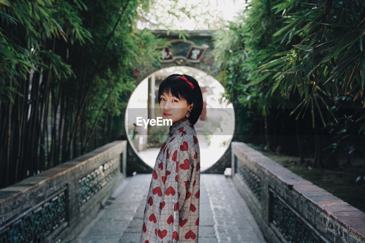 Portrait of a girl standing against trees