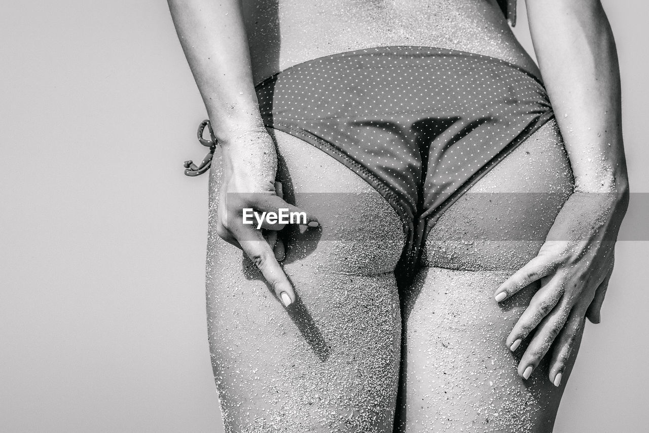Rear view midsection of woman in bikini showing obscene gesture