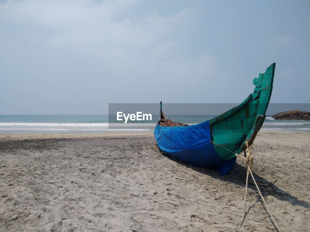Scenic view of beach against sky, traditional wooden fishing boat, kovalam beach, thiruvananthapuram