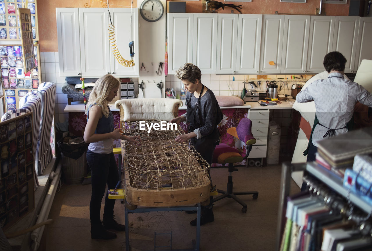 Female workers making chaise longue together at workshop