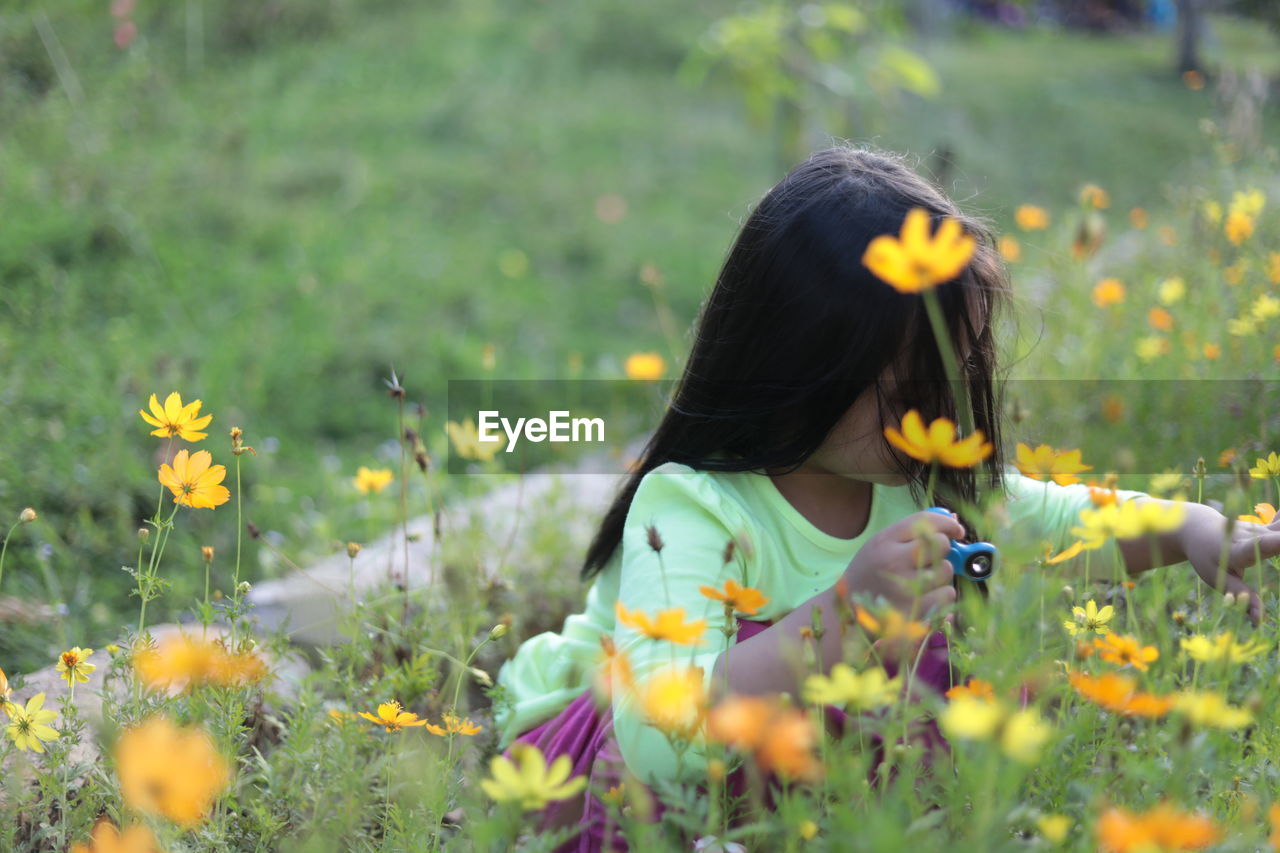 Girl with fidget spinner by flowers on field