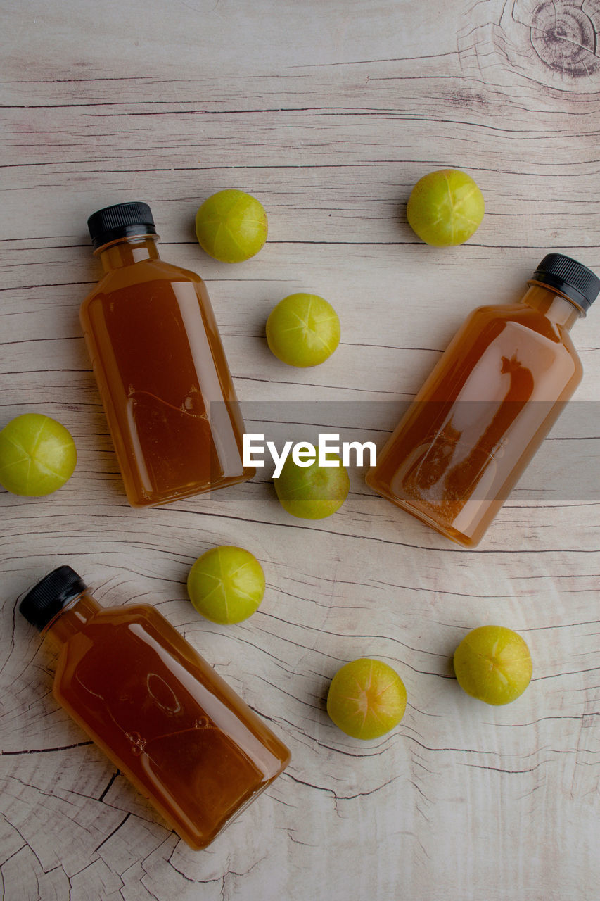 Ayurvedic amla or indian gooseberry juice in a bottle, healthy diet on wood table background