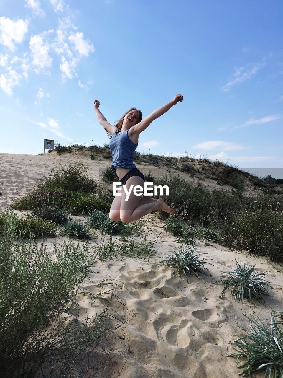 Full length of young woman jumping on sand