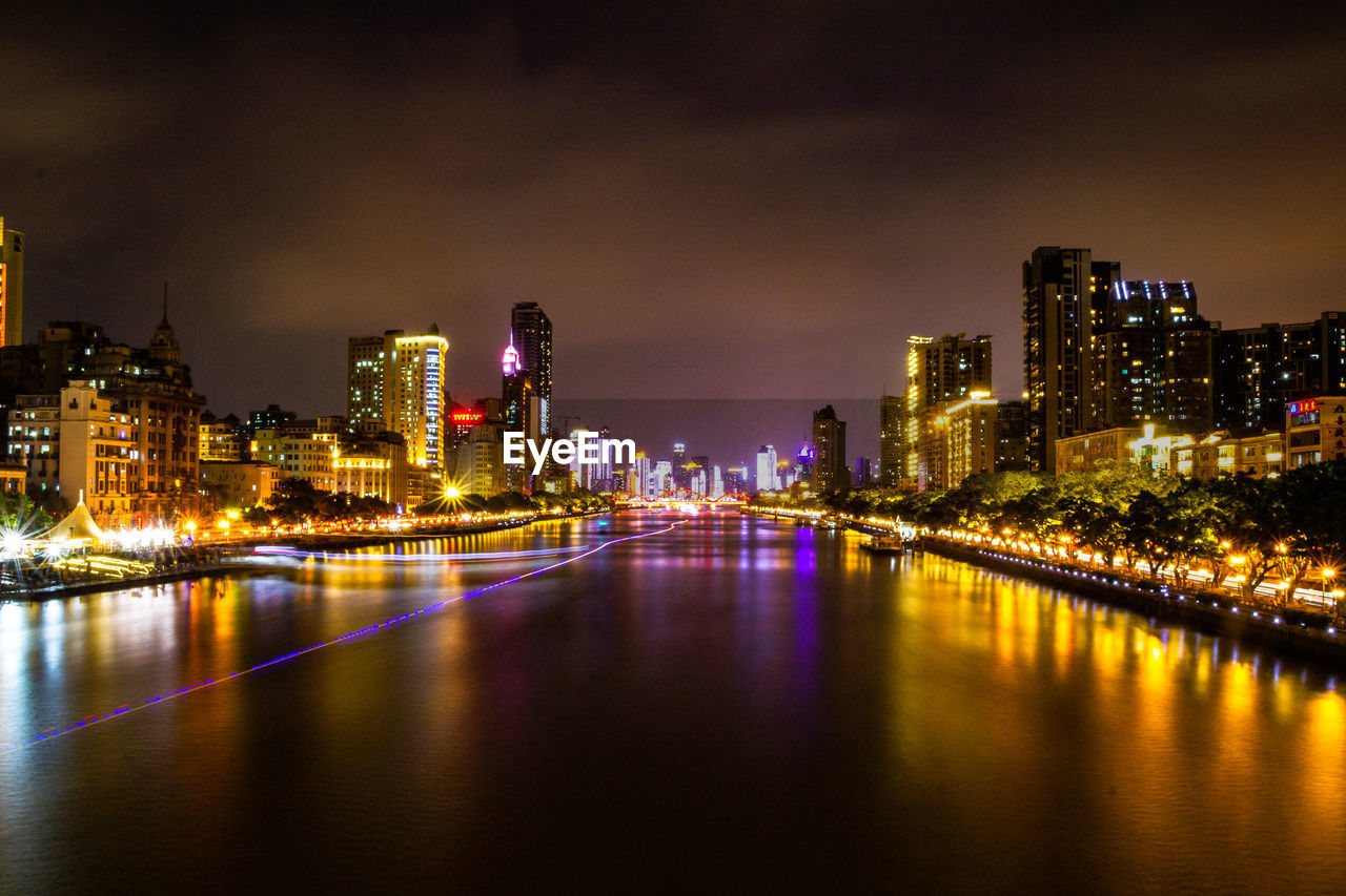 River amidst illuminated buildings against sky at night