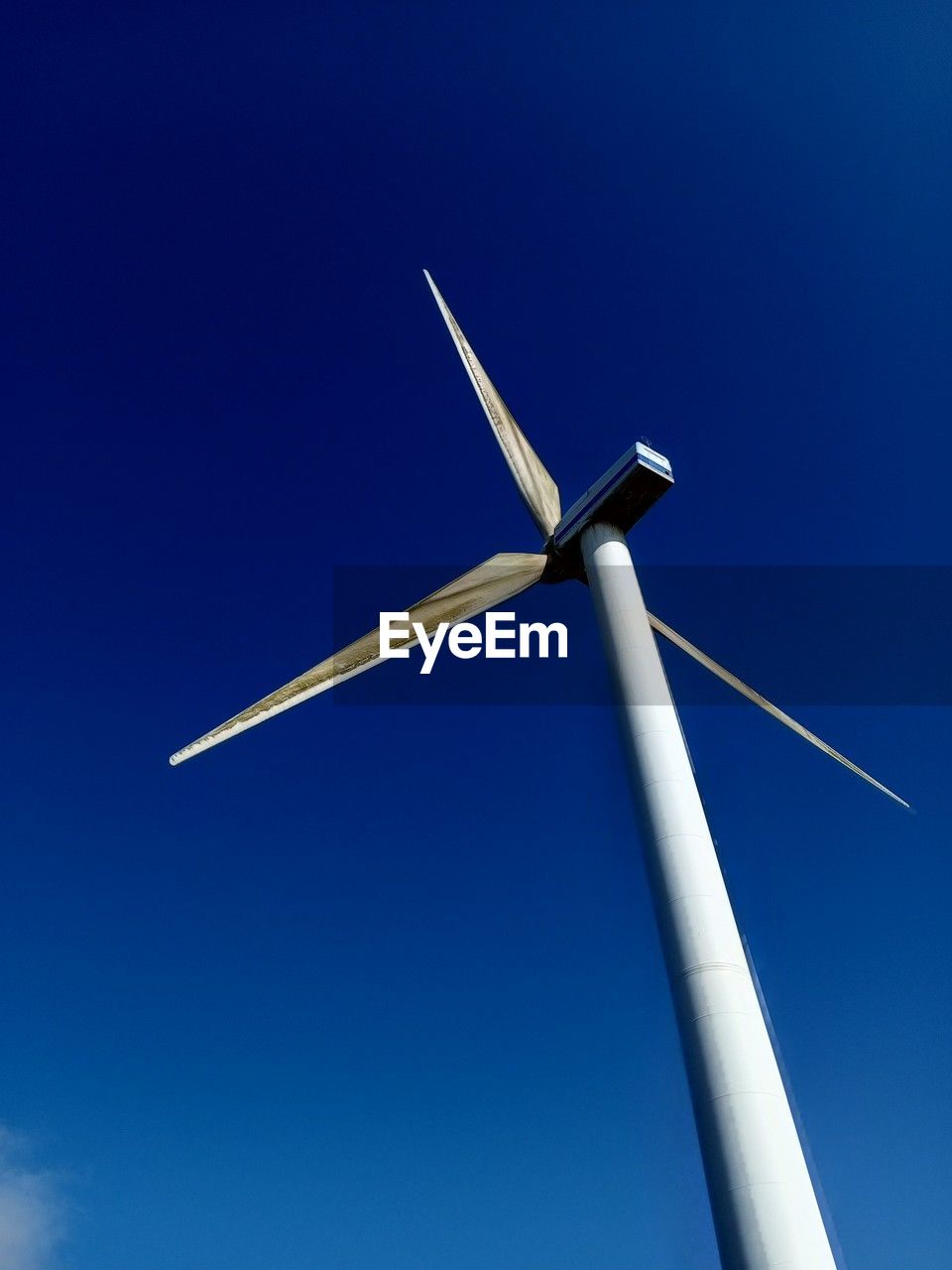 low angle view of wind turbine against clear blue sky
