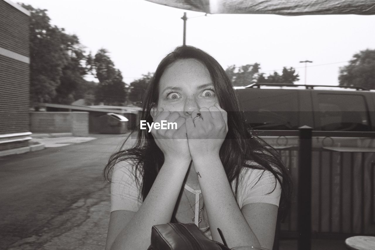 Portrait of surprised woman against car