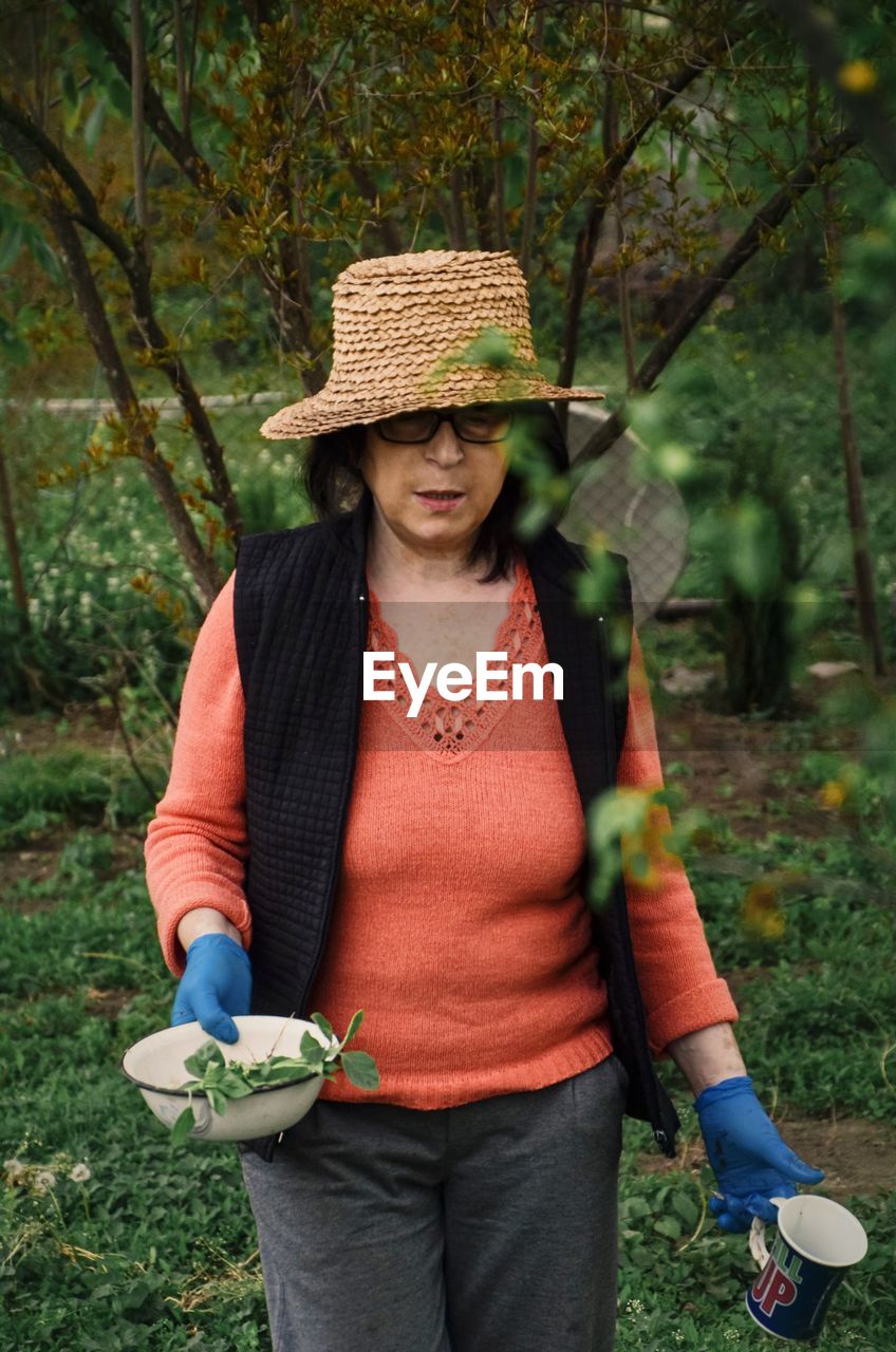 Mid adult man wearing hat while holding plants