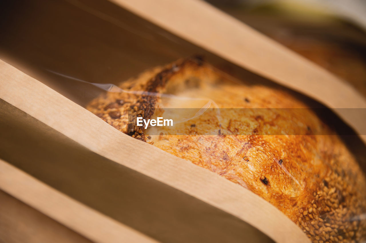 A loaf of white artisan hot bread in a paper bag with transparent inserts healthy food. 