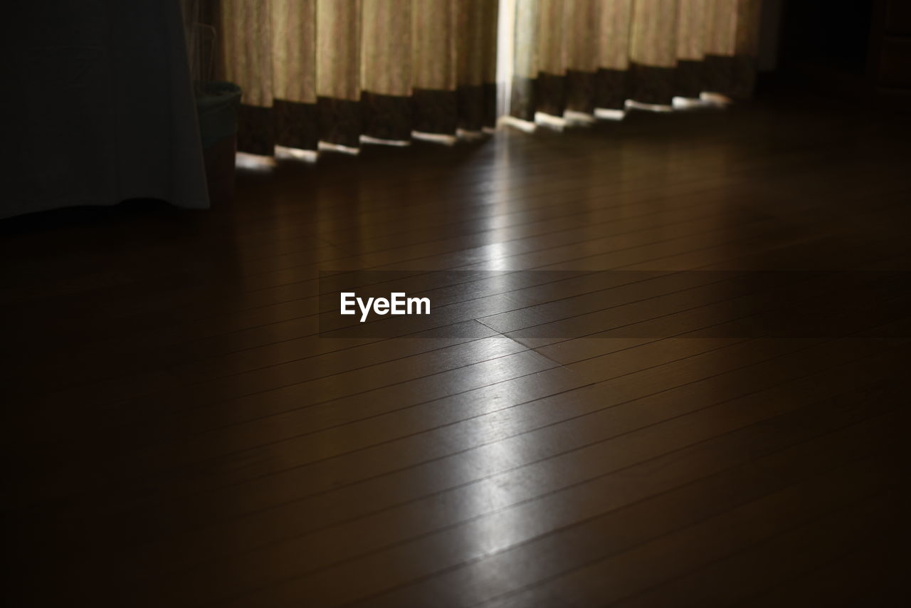 High angle view of hardwood floor with sunlight from curtain in house