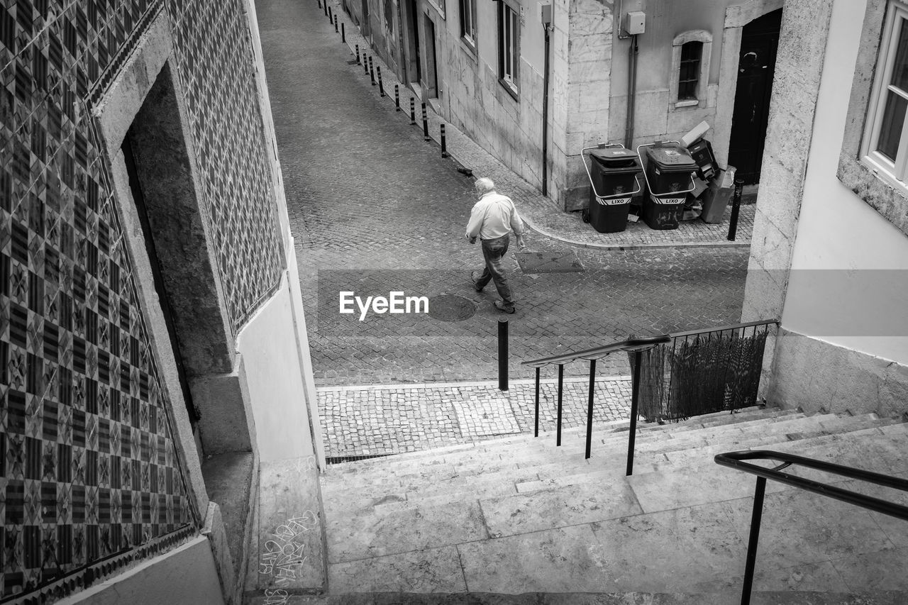 HIGH ANGLE VIEW OF MAN WALKING ON RAILING