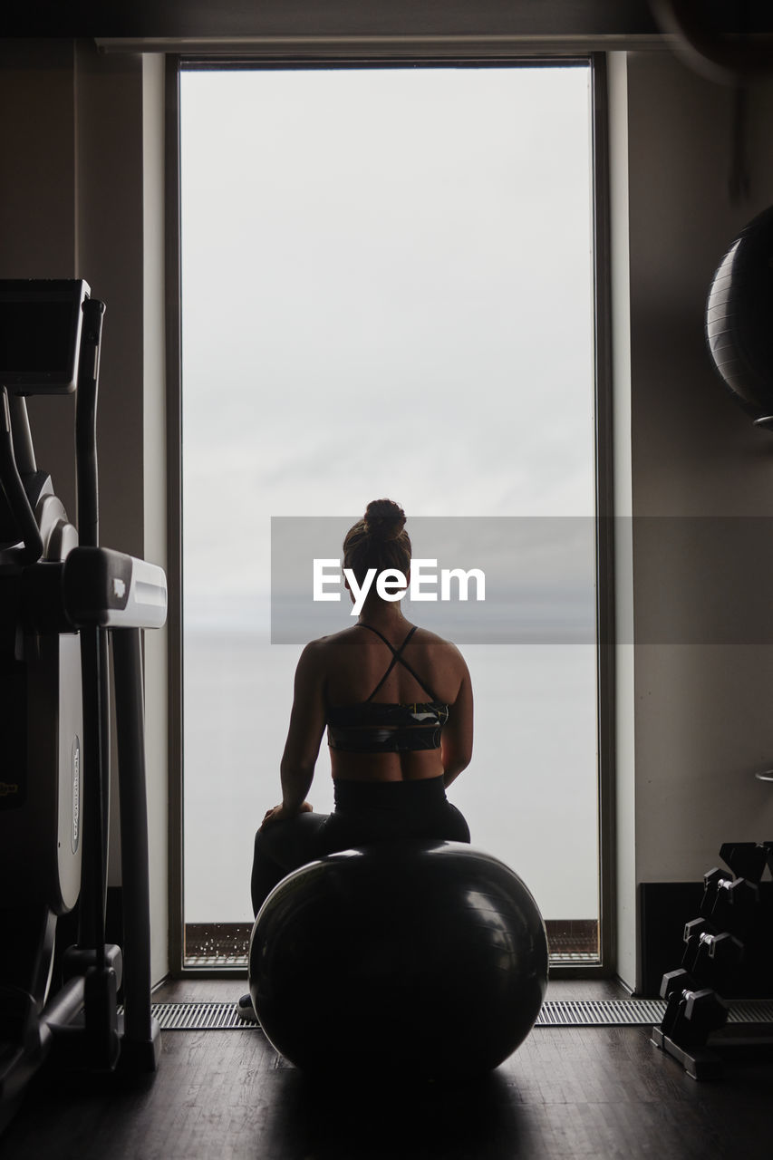 Woman on fitness ball looking through window