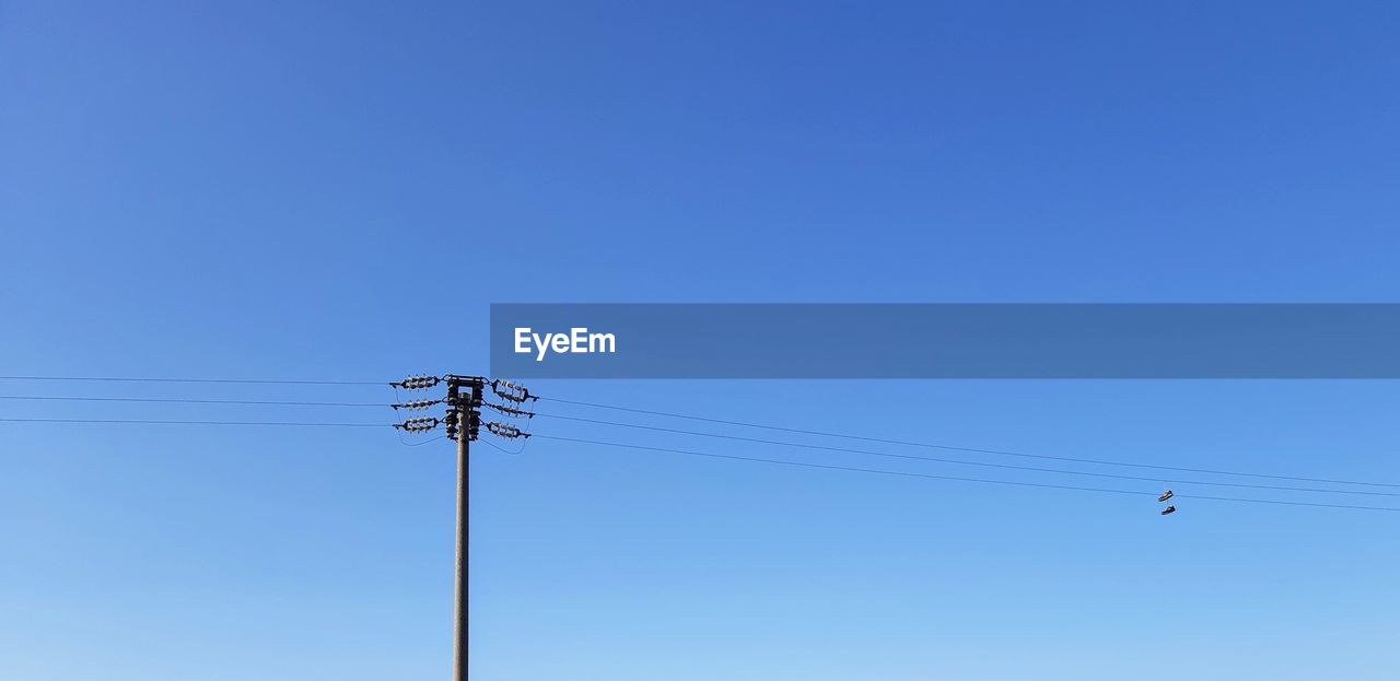 LOW ANGLE VIEW OF BIRDS ON CABLE AGAINST CLEAR BLUE SKY