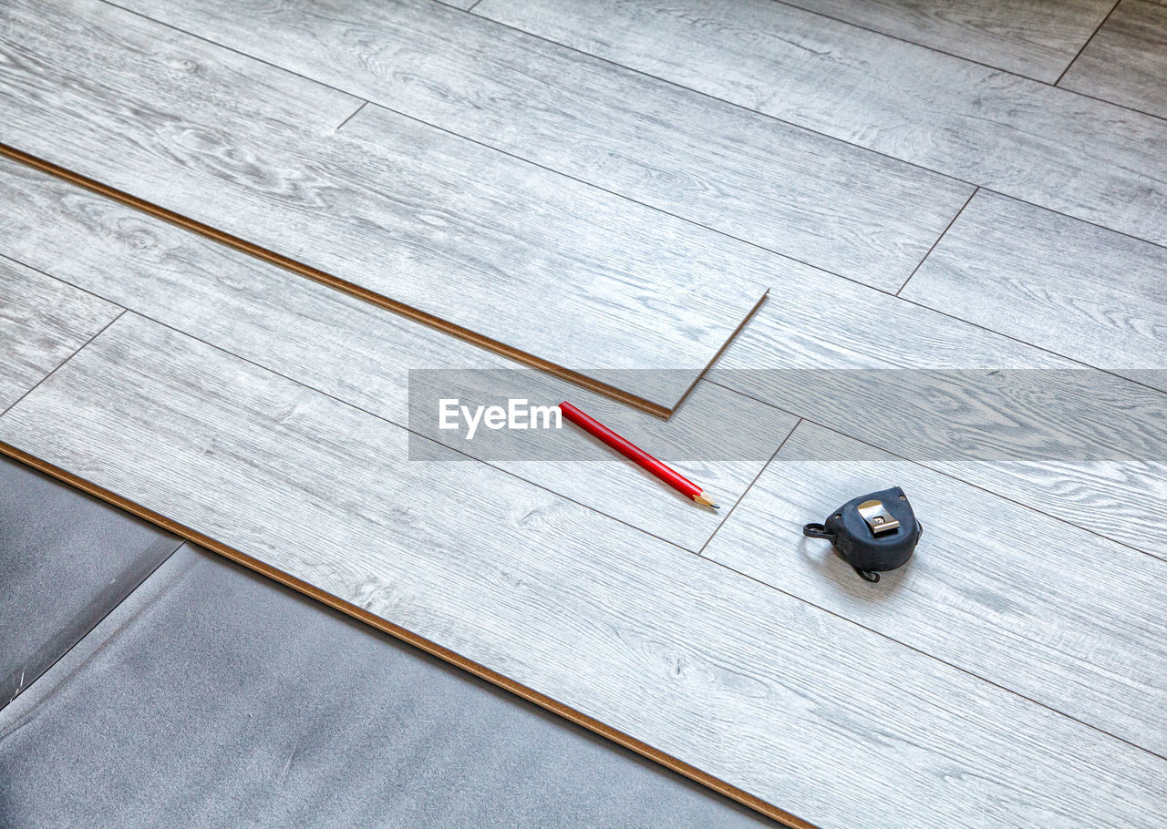 High angle view of pencil with tape measure on wooden table