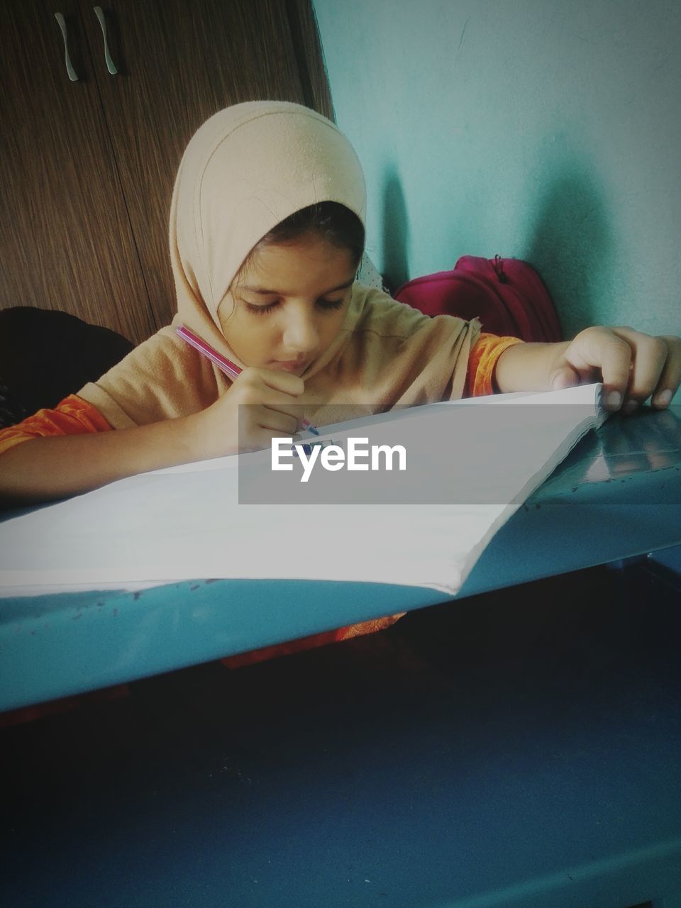Girl wearing hijab studying while sitting at home
