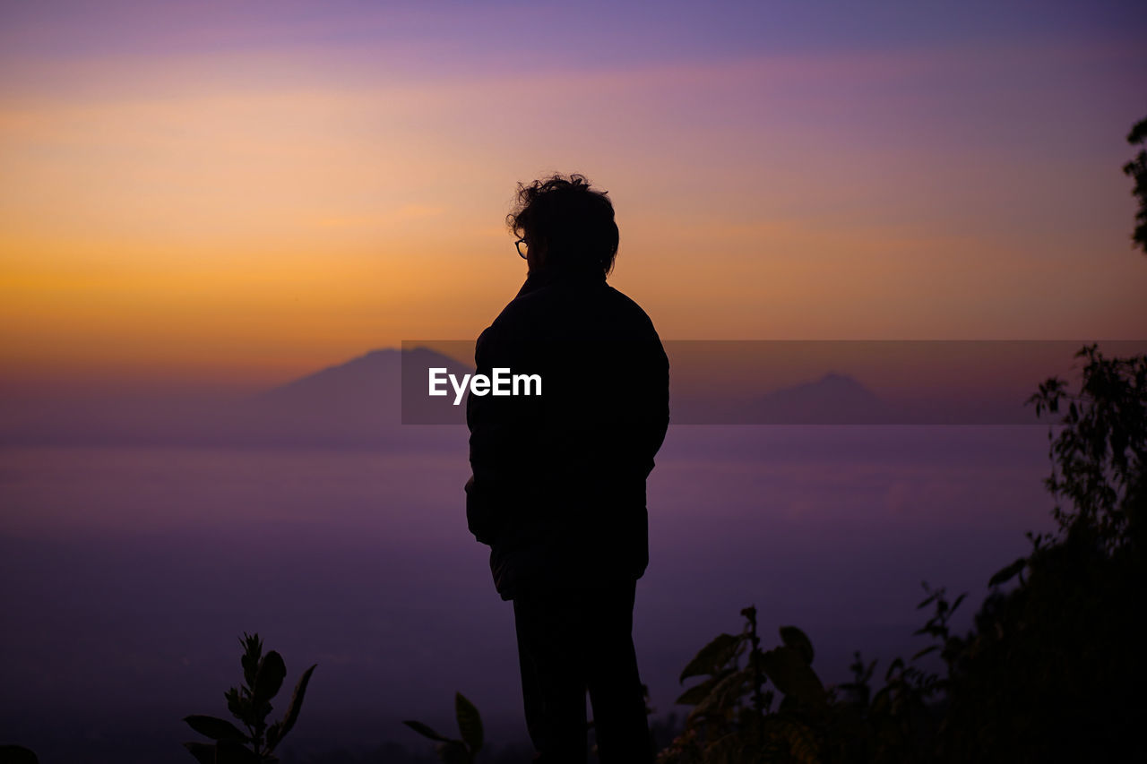 Silhouette man standing against orange sky