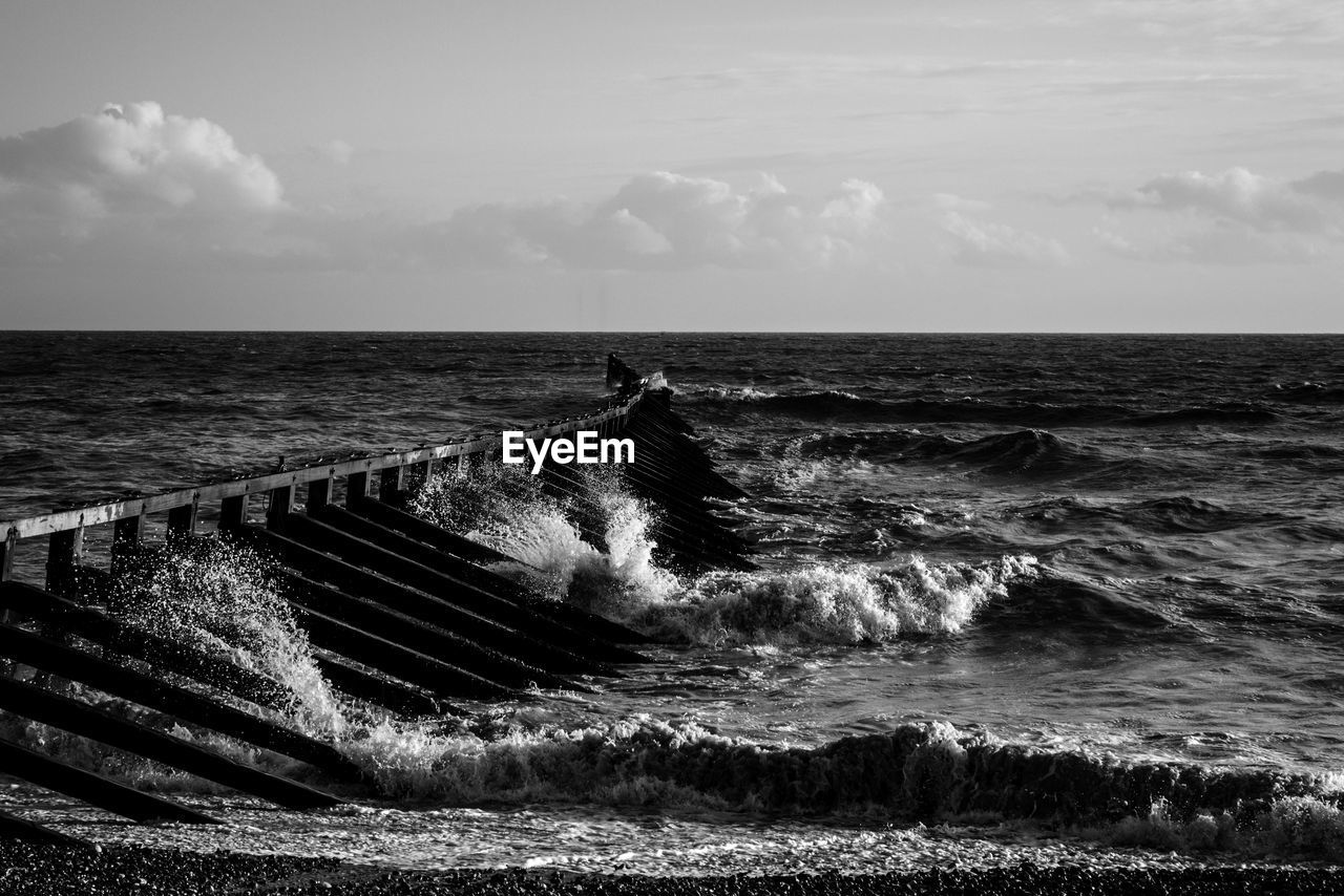 Waves splashing on metallic structure against sky