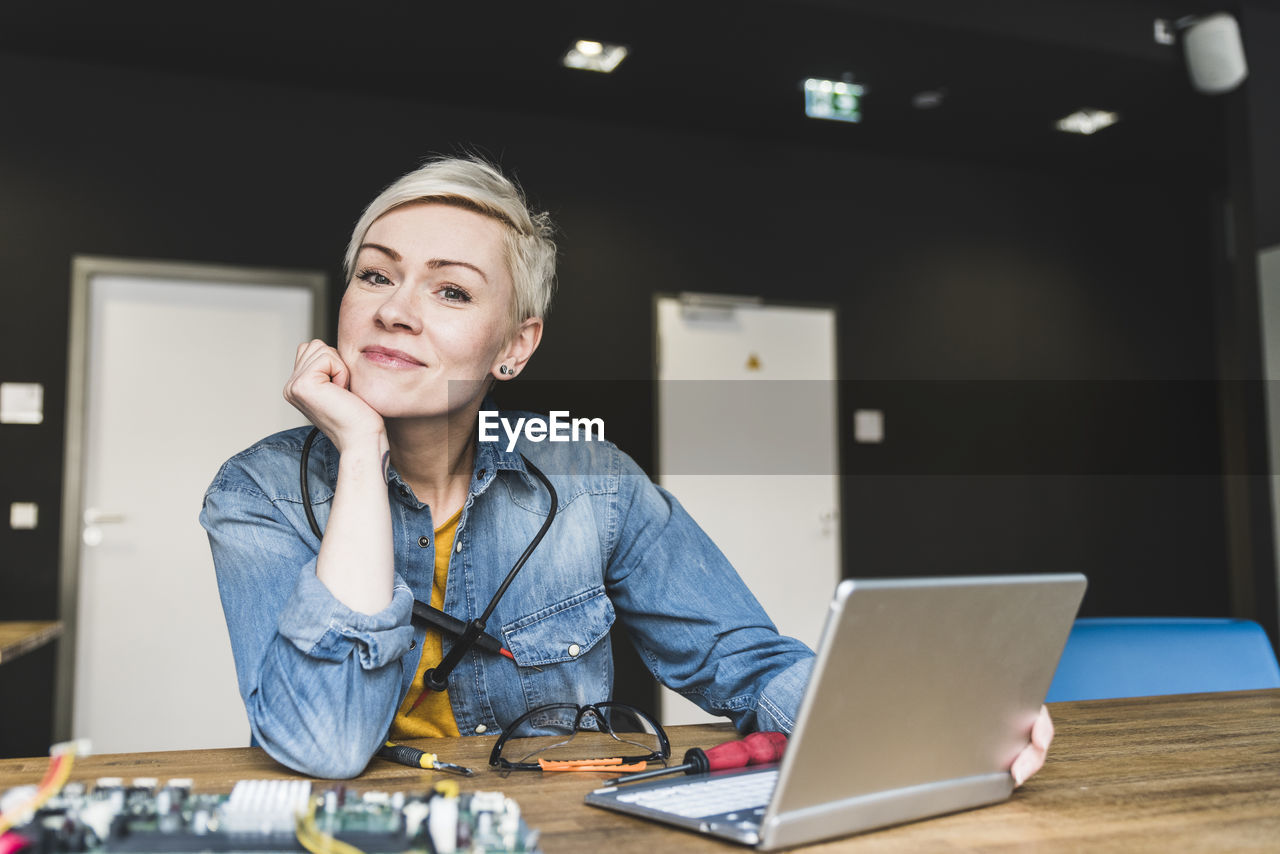 Portrait of smiling woman with laptop and computer equipment