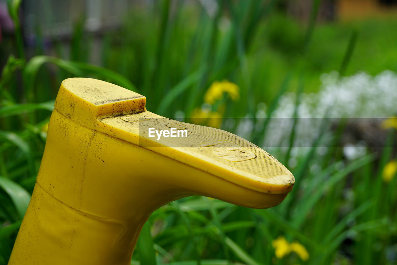 Close-up of yellow rubber boot against plants