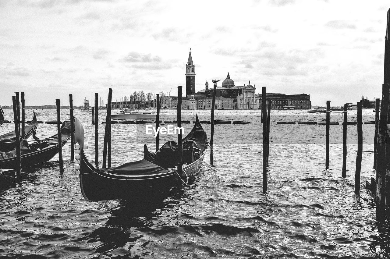 View of wooden post in sea against buildings