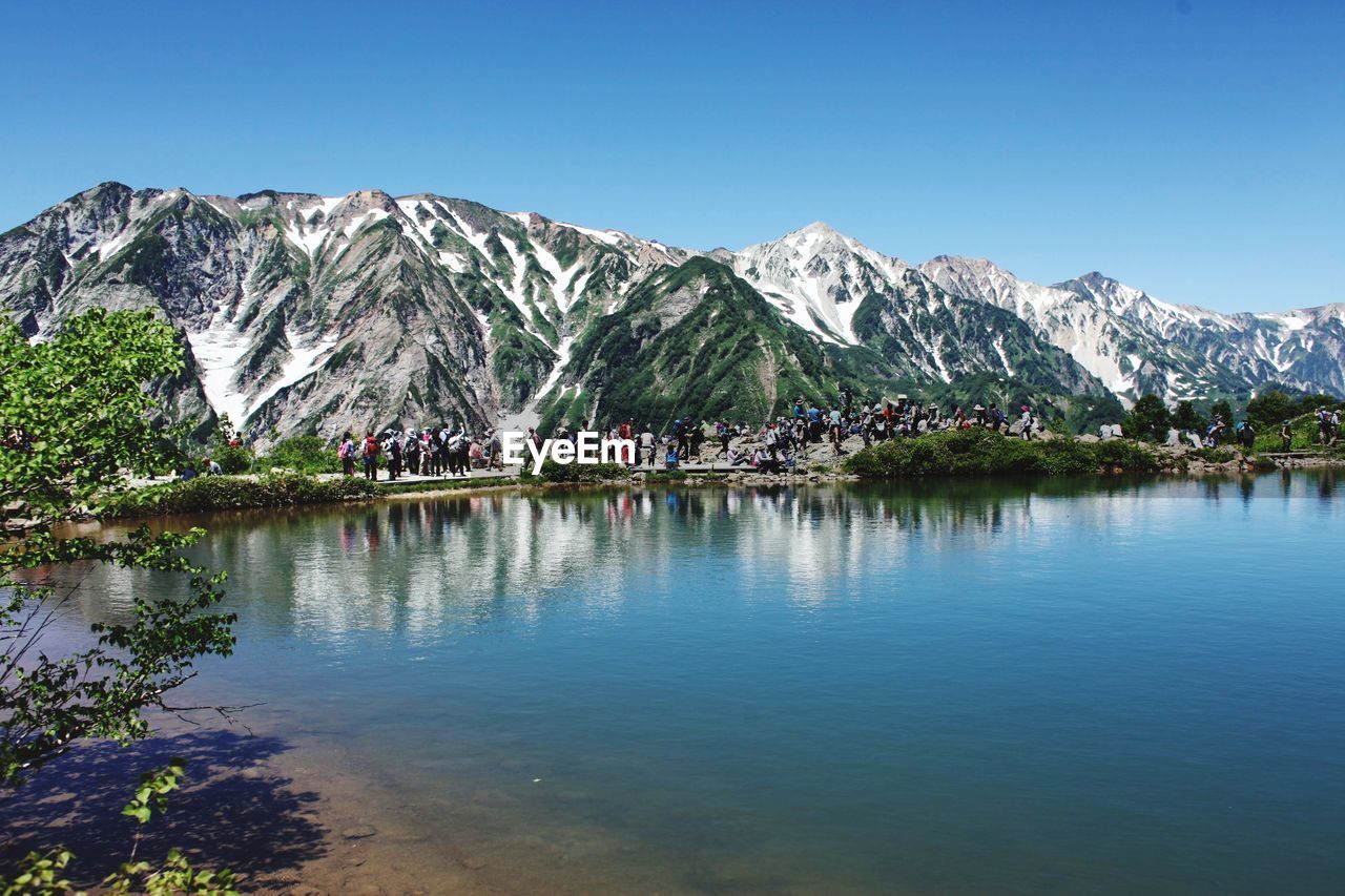 Scenic view of lake and mountains against clear blue sky