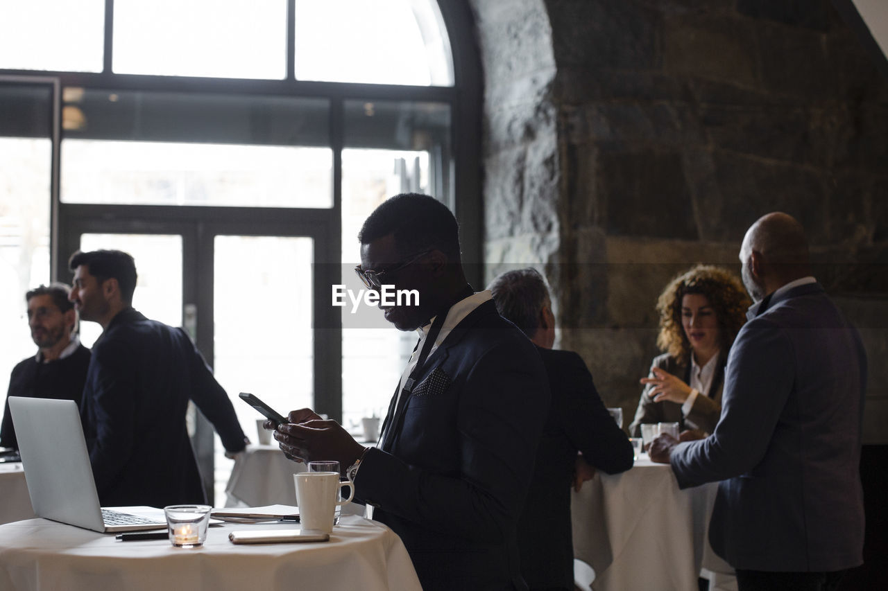 Side view of businessman using smart phone at seminar