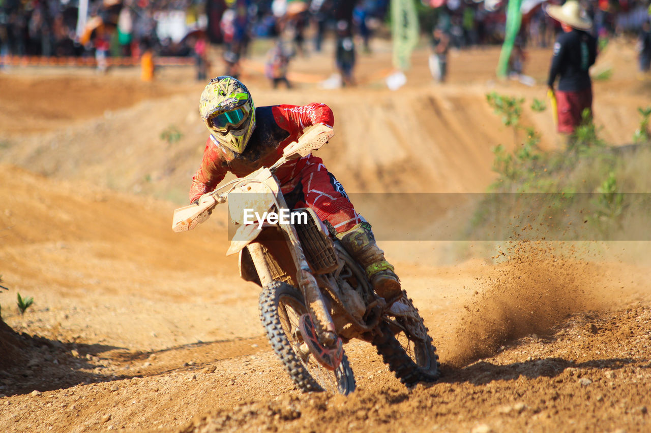 REAR VIEW OF PEOPLE RIDING MOTORCYCLE ON DIRT ROAD