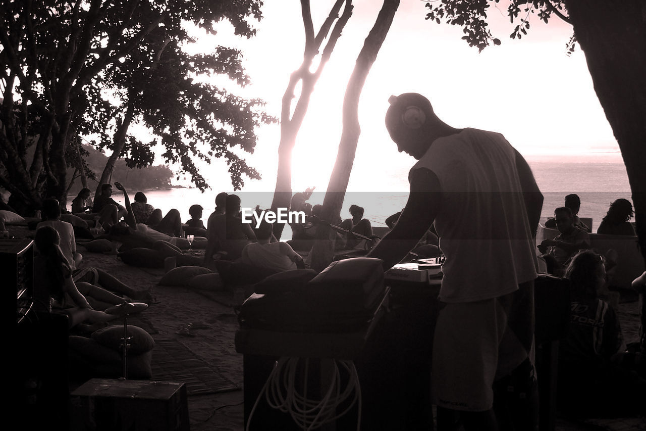 SILHOUETTE OF PEOPLE SITTING IN FRONT OF TREE