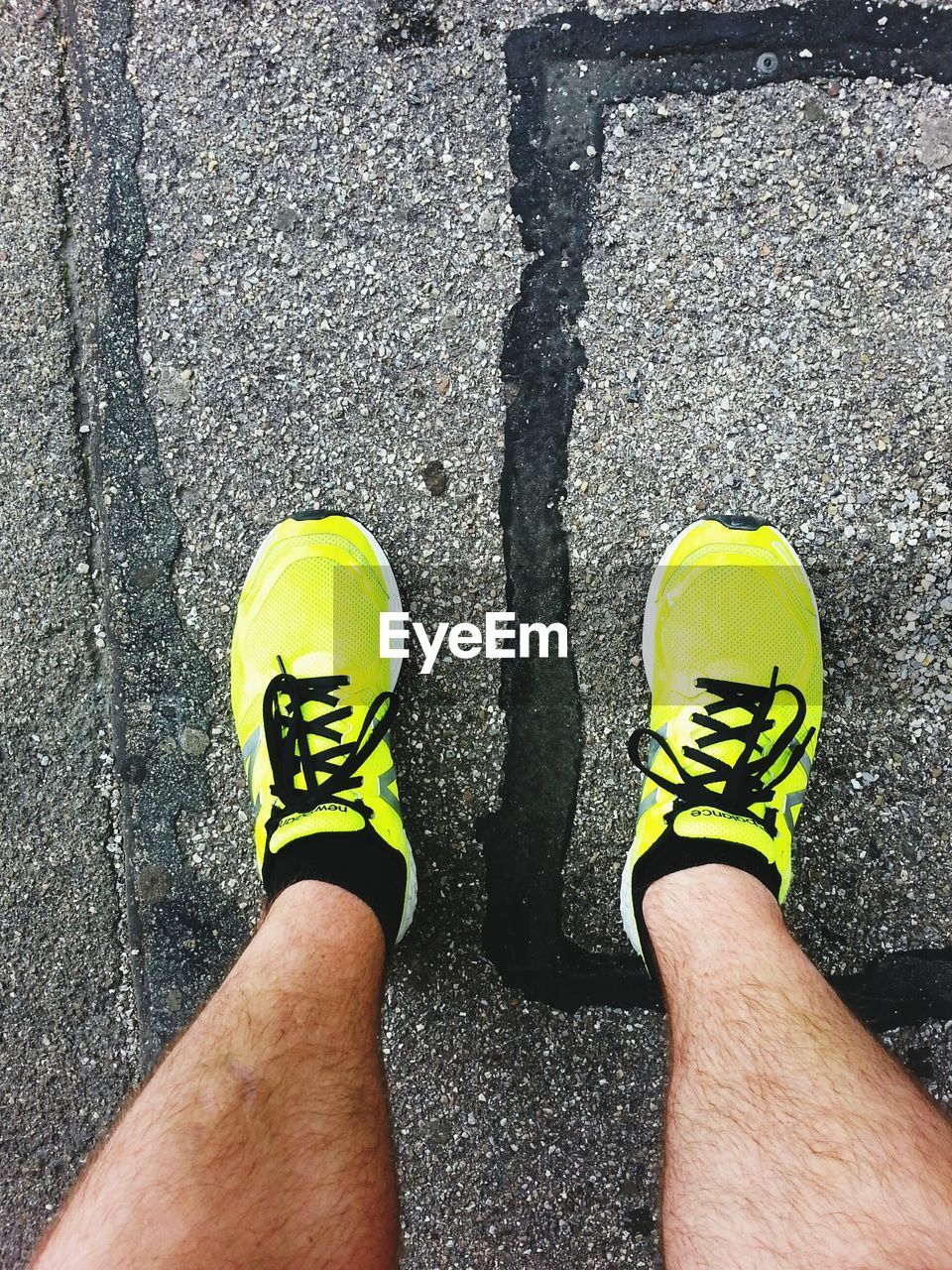 LOW SECTION OF MAN WEARING SHOES STANDING ON YELLOW