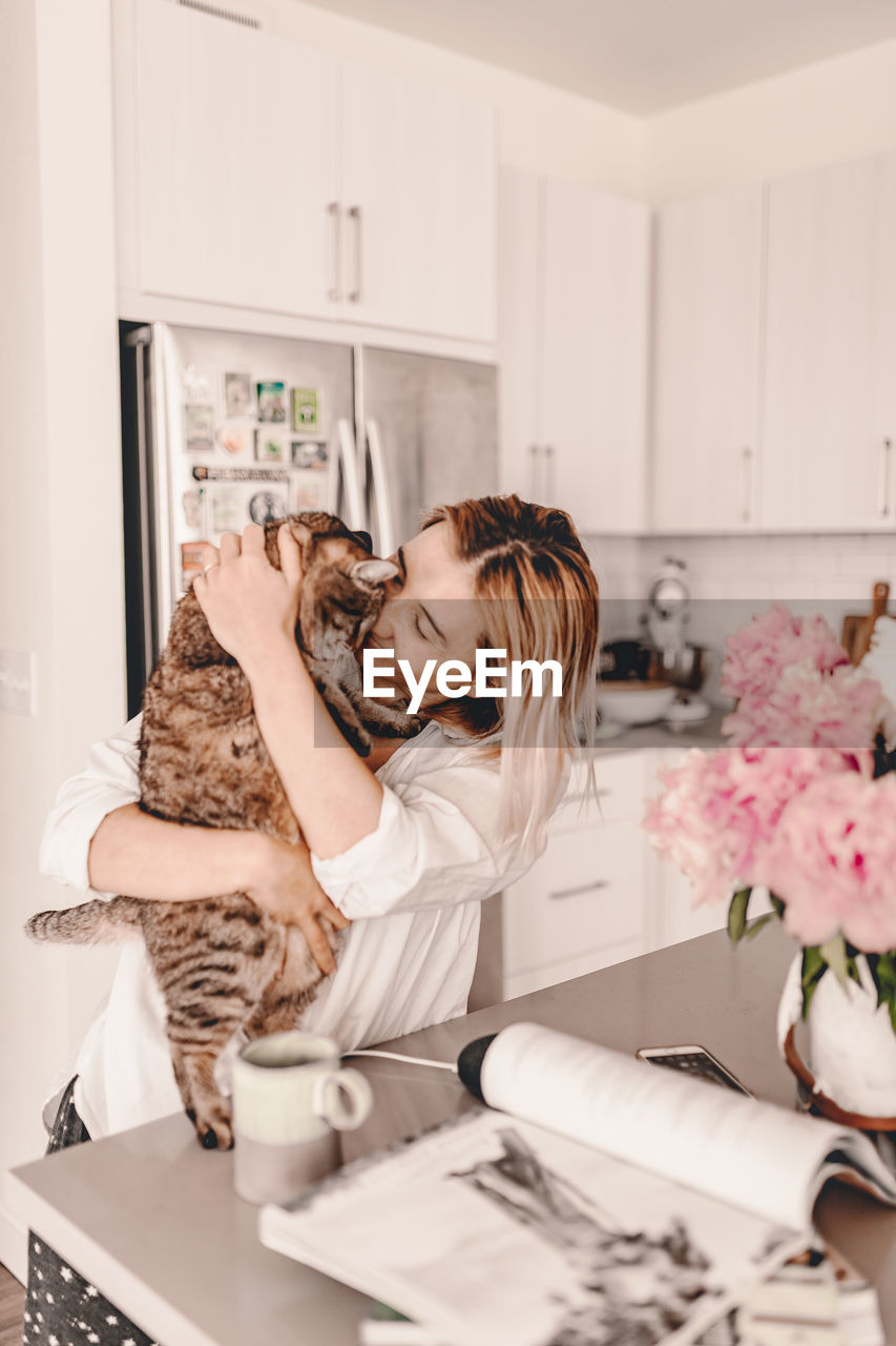 YOUNG WOMAN WITH CAT IN HOME