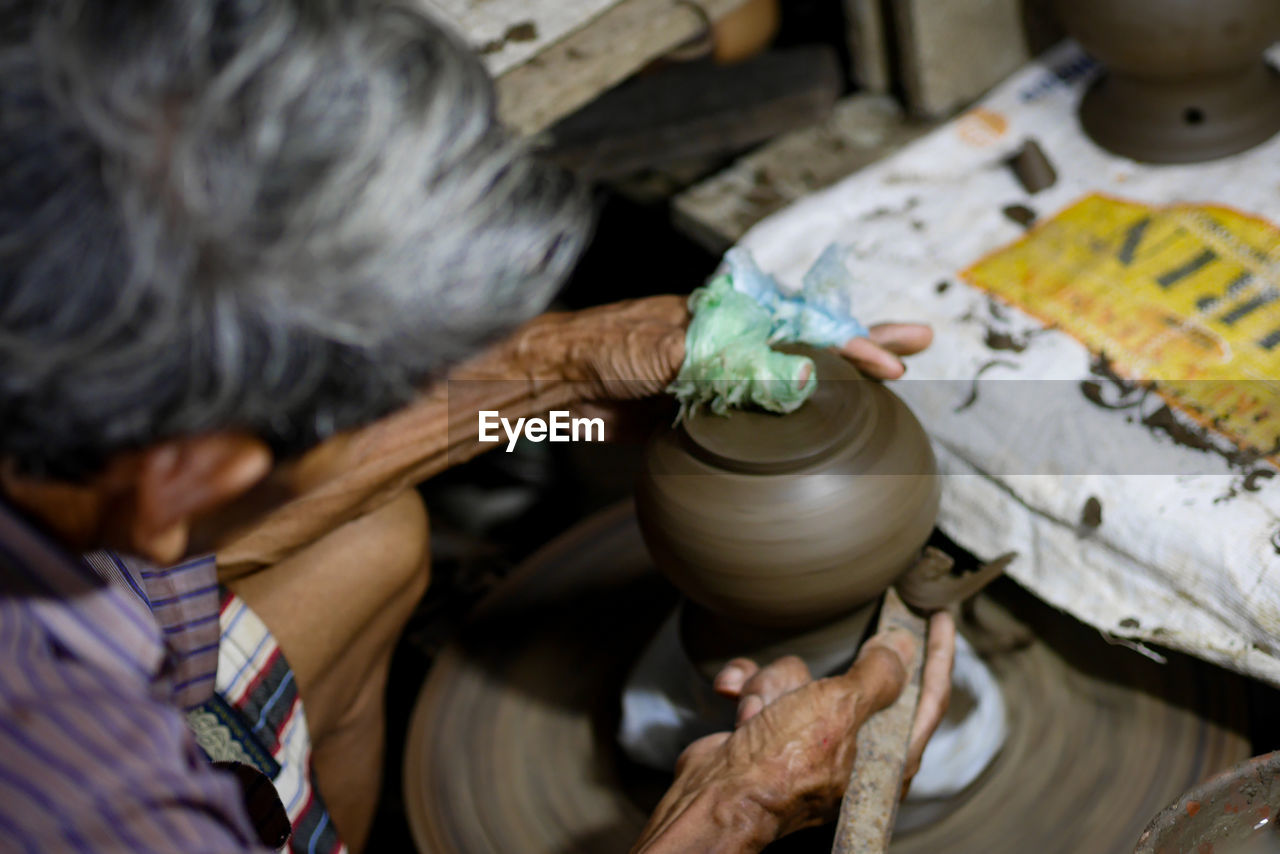 Cropped hands of man making pottery in workshop