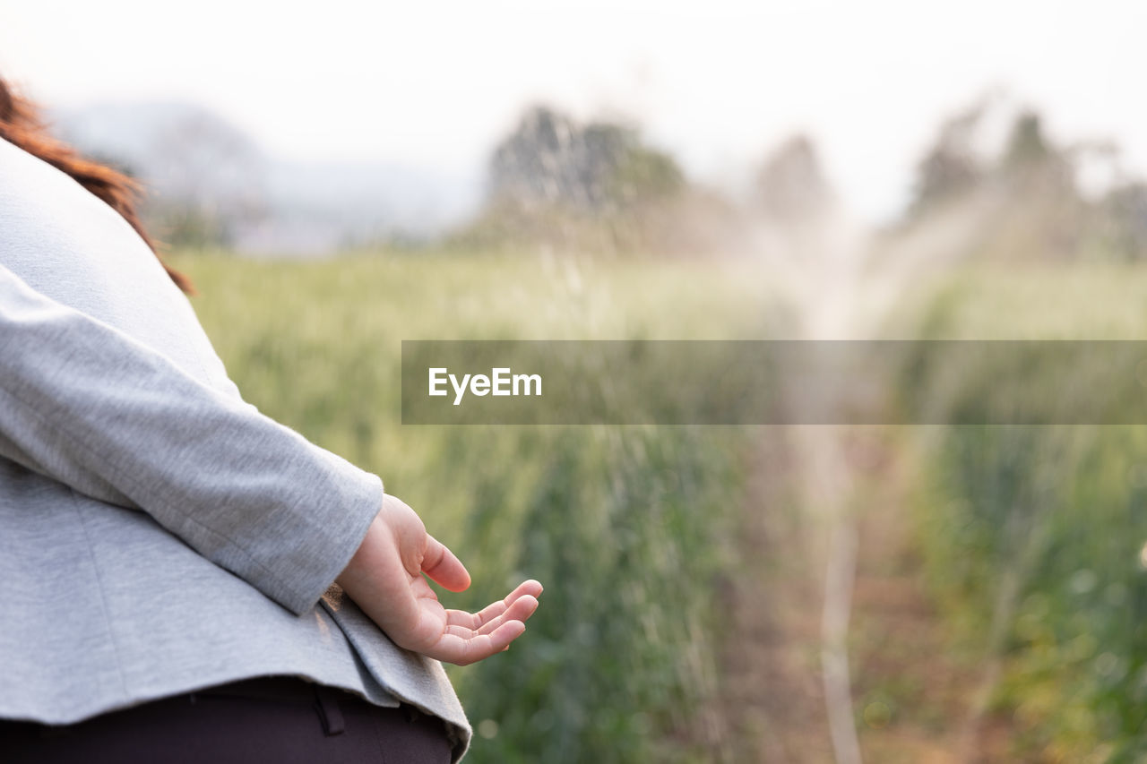 Midsection of woman hand on field