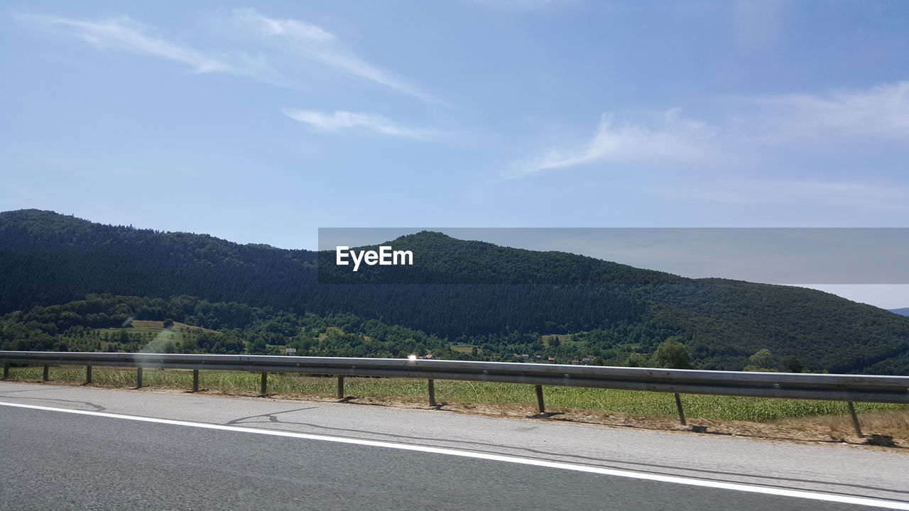 Scenic view of country road and green mountains against sky