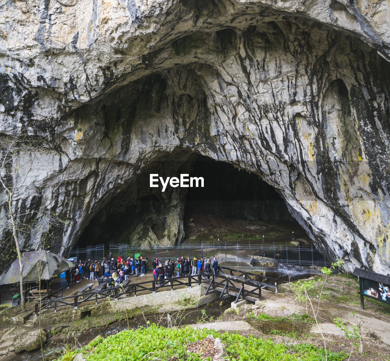 GROUP OF PEOPLE ON ROCK WITH CAVE