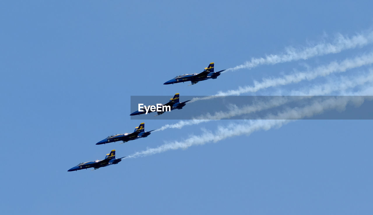 Low angle view of airshow flying against sky