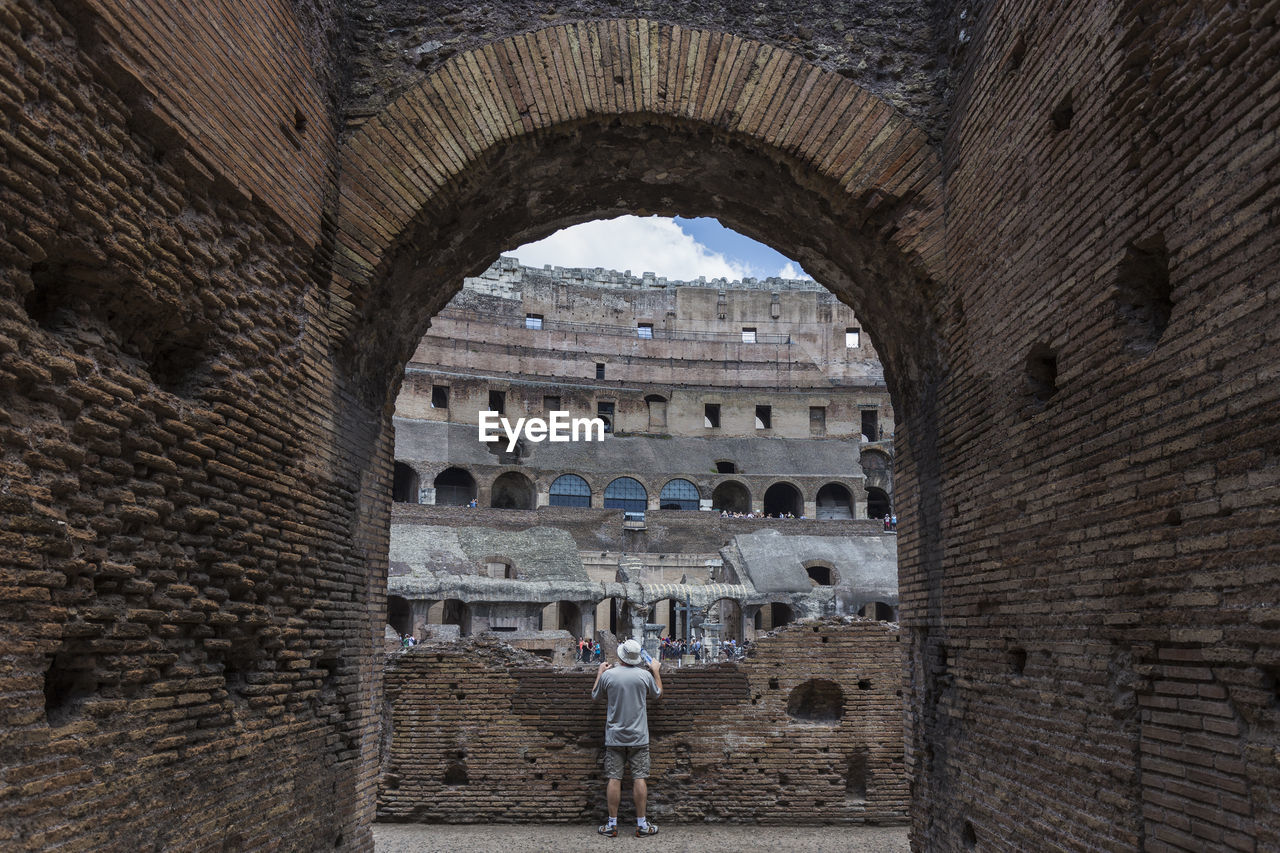 Rear view of male tourist visiting coliseum