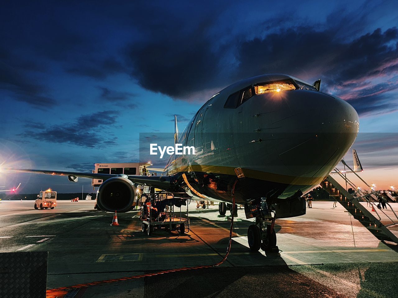 Airplane on airport runway against sky at dusk