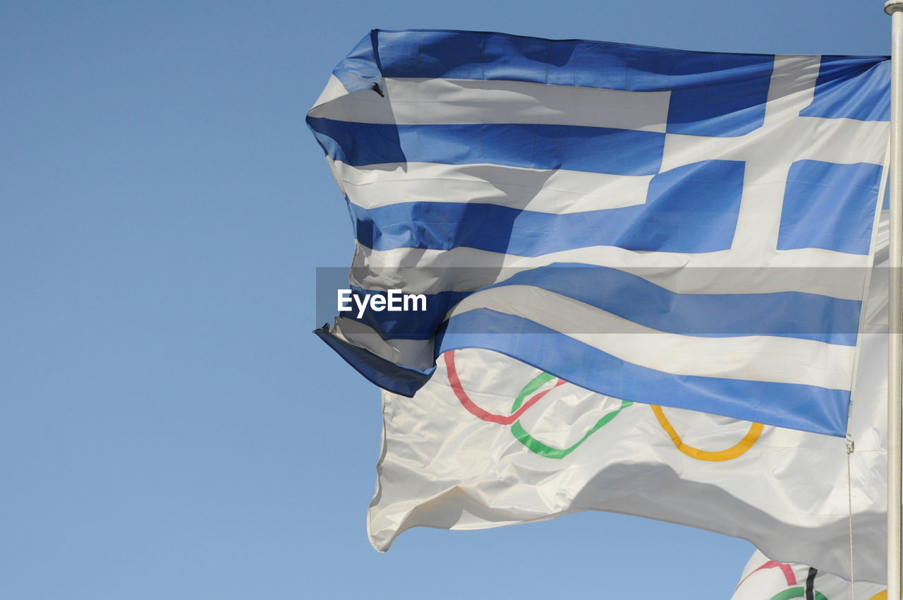 Low angle view of flags against clear blue sky